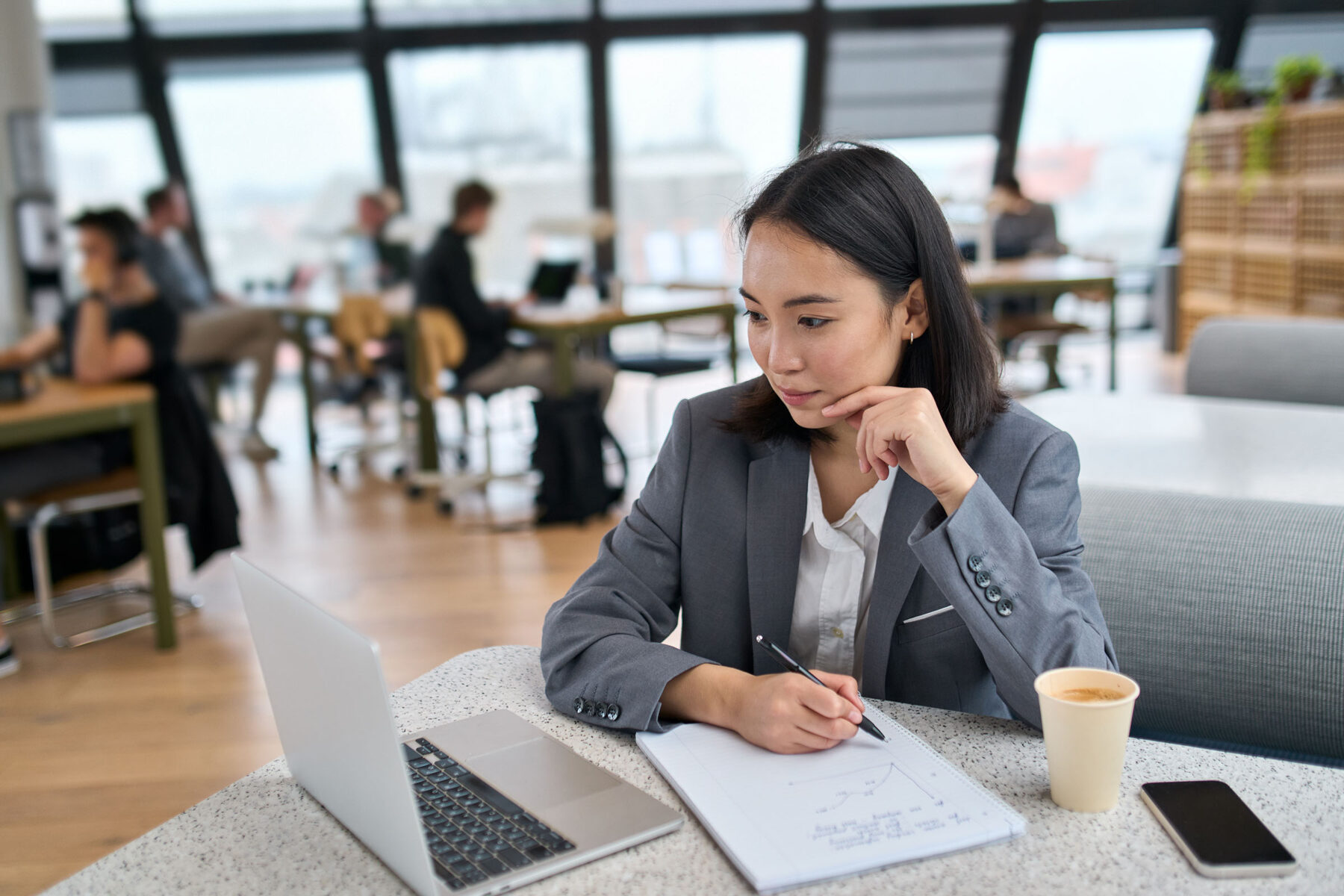 Young Asian business woman using laptop working in big modern office.