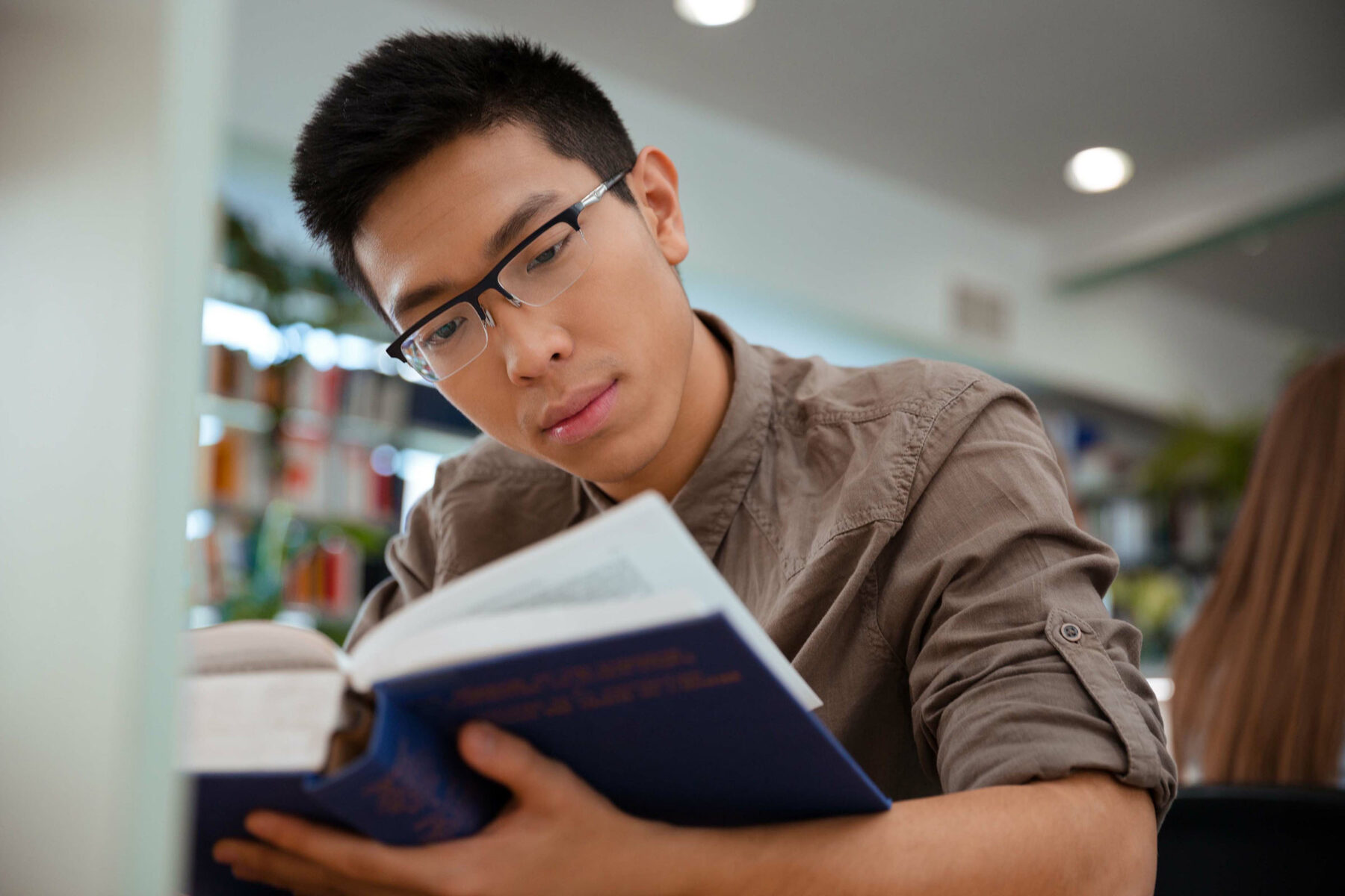 Asian male student reading book in university